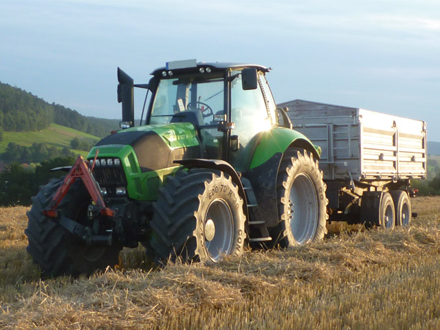 Traktor mit Anhänger auf einem frisch gedräschtem Feld